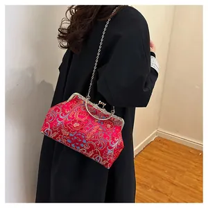 Detailed view of red embroidered silk kiss-lock bag with floral pattern and chain strap