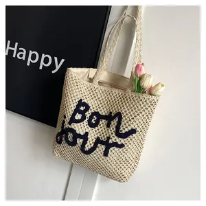 Detailed close-up of hollow straw tote bag with Bonjour embroidery and tulip decoration