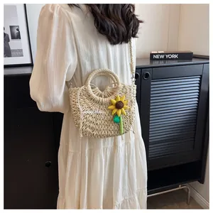 Detail of beige woven straw handbag with Goodday embroidery and sunflower charm