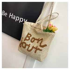 Detail of woven straw bag showing Bonjour embroidery and secure zipper closure