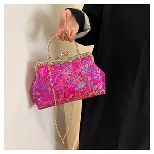 Detail of pink embroidered silk handbag with floral patterns and gold metal handle