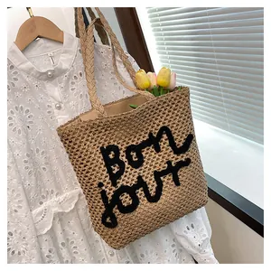 Detailed embroidery of 'bon jour' on a hollow woven straw tote bag for summer beach holidays