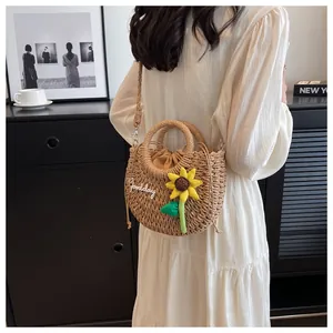 Detail of woven straw bag with yellow sunflower charm and embroidered Goodday text
