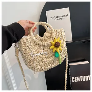 Detail of straw woven bag with goodday embroidery and a sunflower charm on strap