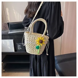 Detail of straw bucket bag with sunflower embroidery and woven shoulder strap