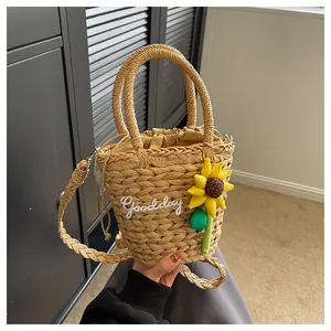 Detail of straw bucket bag with sunflower embroidery, Goodday text, and drawstring pouch