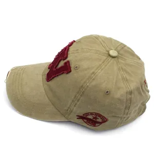 Dettaglio macro del cappellino da baseball kaki con bordi consumati e ricamo rosso vintage
