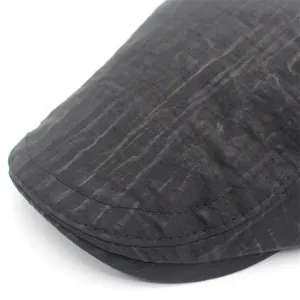 Detail view of double-stitched brim and water-resistant wrinkled fabric on grey flat cap
