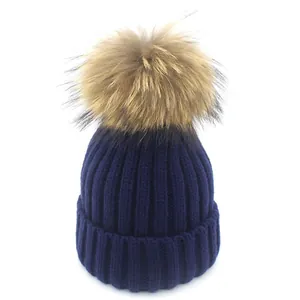 Dunkelblaue Rippstrickmütze mit großem flauschigem Pelzbommel für wohlige Winterwärme