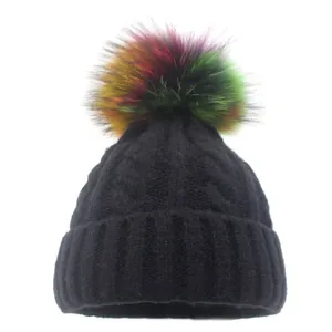 Detail of black thick knit beanie featuring a vibrant multi-color faux fur pom-pom topper