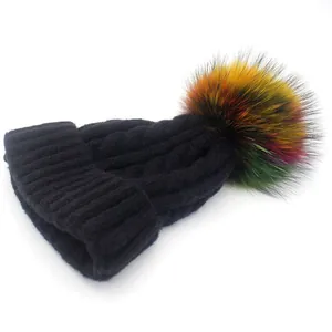 Close-up of black cable knit beanie featuring a colorful fluffy faux fur pom-pom detail
