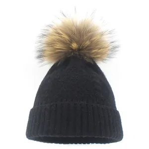 Black ribbed knit winter beanie for women featuring a large natural brown fur pompom