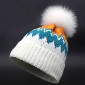 Winter-Strickmütze mit weißem Bommel und buntem Zickzack-Muster in Blau und Orange