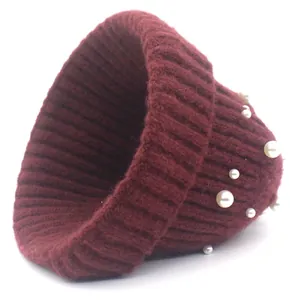 Détail d'un bonnet en tricot côtelé rouge vin orné d'élégantes perles blanches