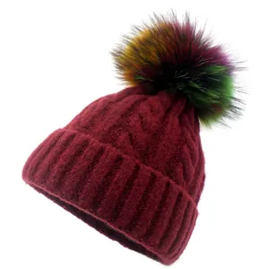 Close-up of wine red chunky cable knit beanie with vibrant multicolored faux fur pom-pom
