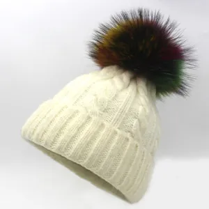 Close-up of beige knit beanie featuring thick cable texture and a colorful faux fur pom-pom