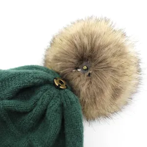 Dark green wool knit beanie featuring a detachable brown faux fur pom pom decoration