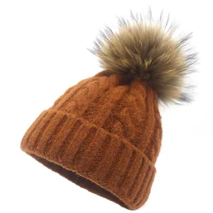 Detailed knit texture of a caramel brown winter beanie with a fluffy pom-pom top