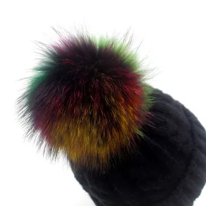 Thick warm black knit beanie with a large colorful rainbow pom-pom on white background