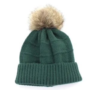 Dark green knitted wool beanie featuring a large brown faux fur pom-pom on top