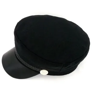 Détail du chapeau de marin noir avec visière en similicuir et bouton métallique argenté