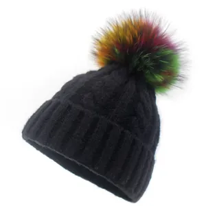 Thick black cable knit beanie with a colorful faux fur pompom for winter warmth
