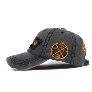 Detail of vintage washed cotton baseball cap with orange eagle embroidery and worn edges