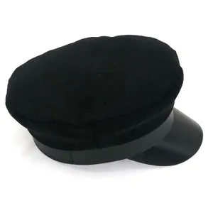 Detail of black wool newsboy hat featuring textured PU leather brim and flat top design