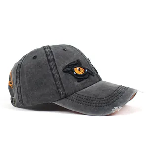 Detail of washed cotton baseball cap featuring eye embroidery and distressed brim edge