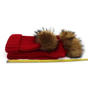 Detail of red knit scarf with raccoon fur pom-poms showing 42cm measurement scale