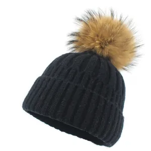 Détail de la maille épaisse et du pompon marron moelleux sur le bonnet d'hiver noir