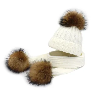 Close-up detail of knitted winter hat and scarf set with fluffy brown faux fur pom poms