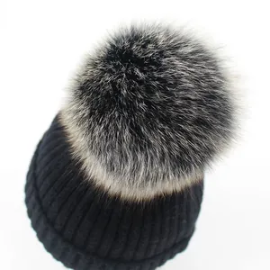 Primer plano del gorro de punto acanalado negro con un pompón de piel muy suave