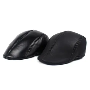 Close-up of matte and glossy black leather flat caps showing texture and stitching details