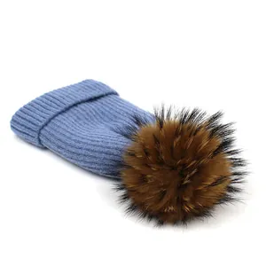 Detail of light blue wool knit beanie with thick texture and fluffy brown pom pom