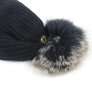 Gorro de punto negro con pompón de piel de zorro real desmontable y detalle de broche dorado