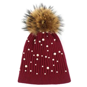 Women's burgundy knit beanie with elegant pearl beads and a large faux fur pompom