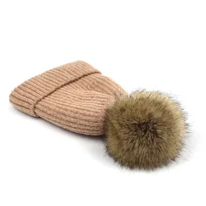 Detail van lichtbruine gebreide muts met zachte pompon van imitatiebont voor de winter