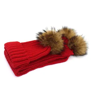 Red knit winter hat for children featuring two fluffy faux fur pom-poms on top