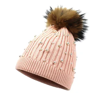 Pink knitted wool beanie for women featuring white pearls and a fluffy faux fur pompom