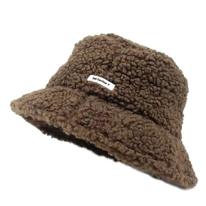 Detail of warm brown teddy faux fur bucket hat featuring a white lettered fabric patch