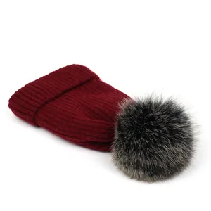 Detalle del gorro de punto granate con textura acanalada y pompón de piel esponjoso