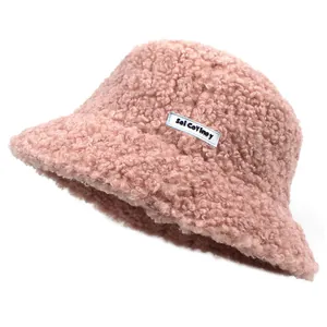 Detail of pink teddy fleece bucket hat with a white rectangular letter logo label
