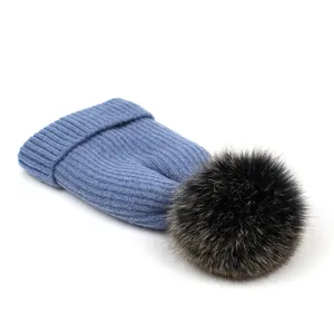 Detalle de gorro de punto acanalado azul con un gran pompón de piel sintética suave