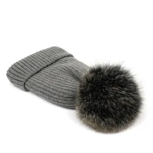 Detalle de gorro de punto gris con un gran pompón de piel sintética marrón muy suave