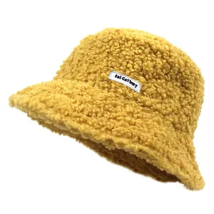 Close-up of yellow teddy fleece bucket hat featuring a white woven letter label
