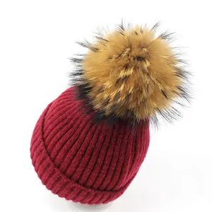 Women's burgundy wool knit beanie with large fluffy raccoon fur pompom for winter