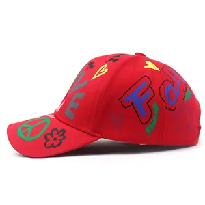 Dettaglio cappello in cotone rosso con graffiti Love e ricamo del segno Peace