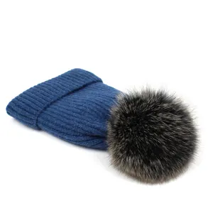 Detalle del tejido de punto acanalado y pompón de piel de zorro suave en el gorro azul