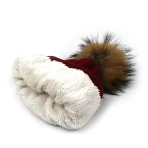 Women's burgundy knit beanie with warm fleece lining and a large faux fur pompom